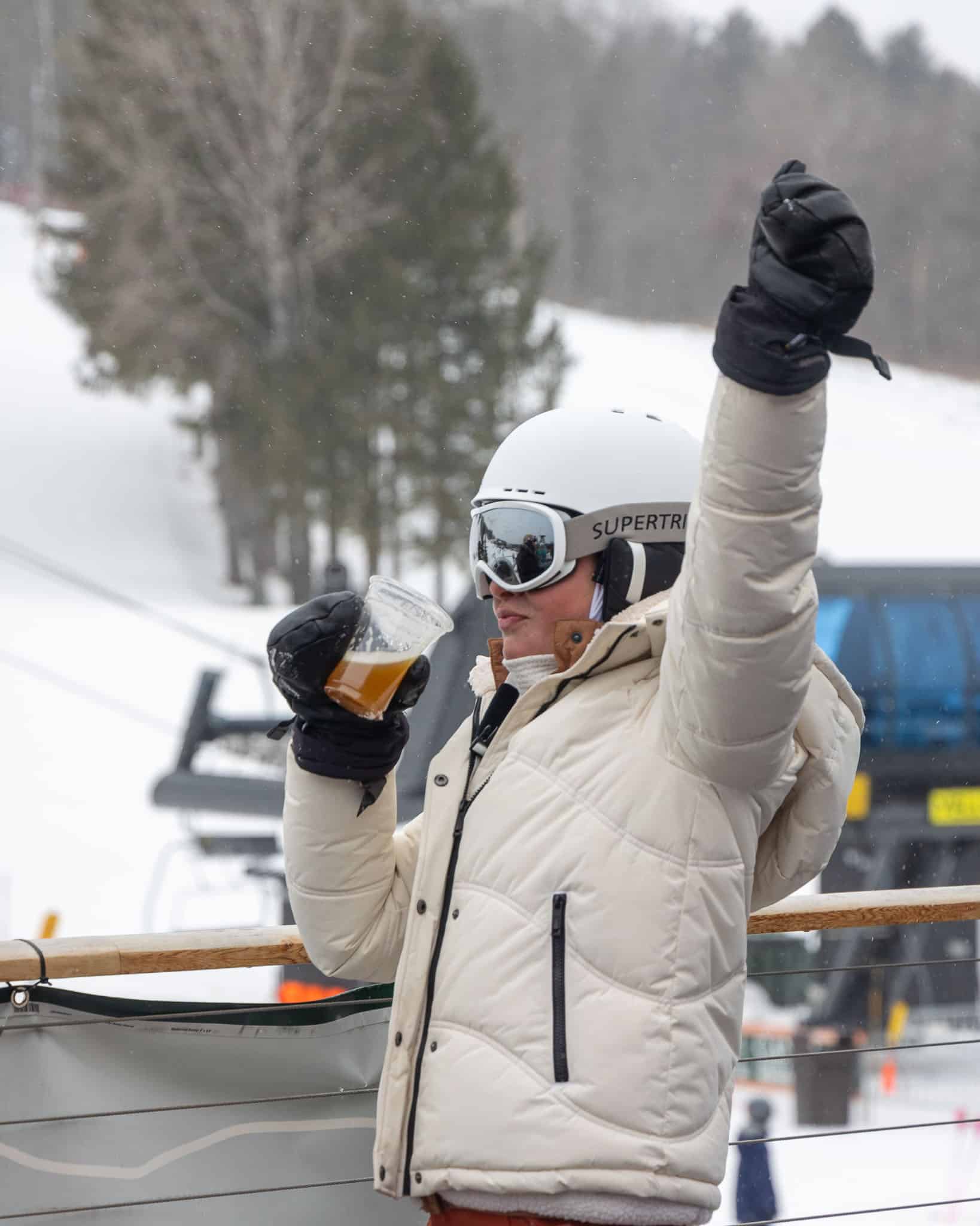 Woman dressed in ski gear, drinking a beer and dancing to music at Bousquet Mountain