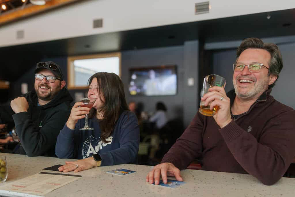 Group of three friends laughing and enjoying a beer together in drifters bar & restaurant