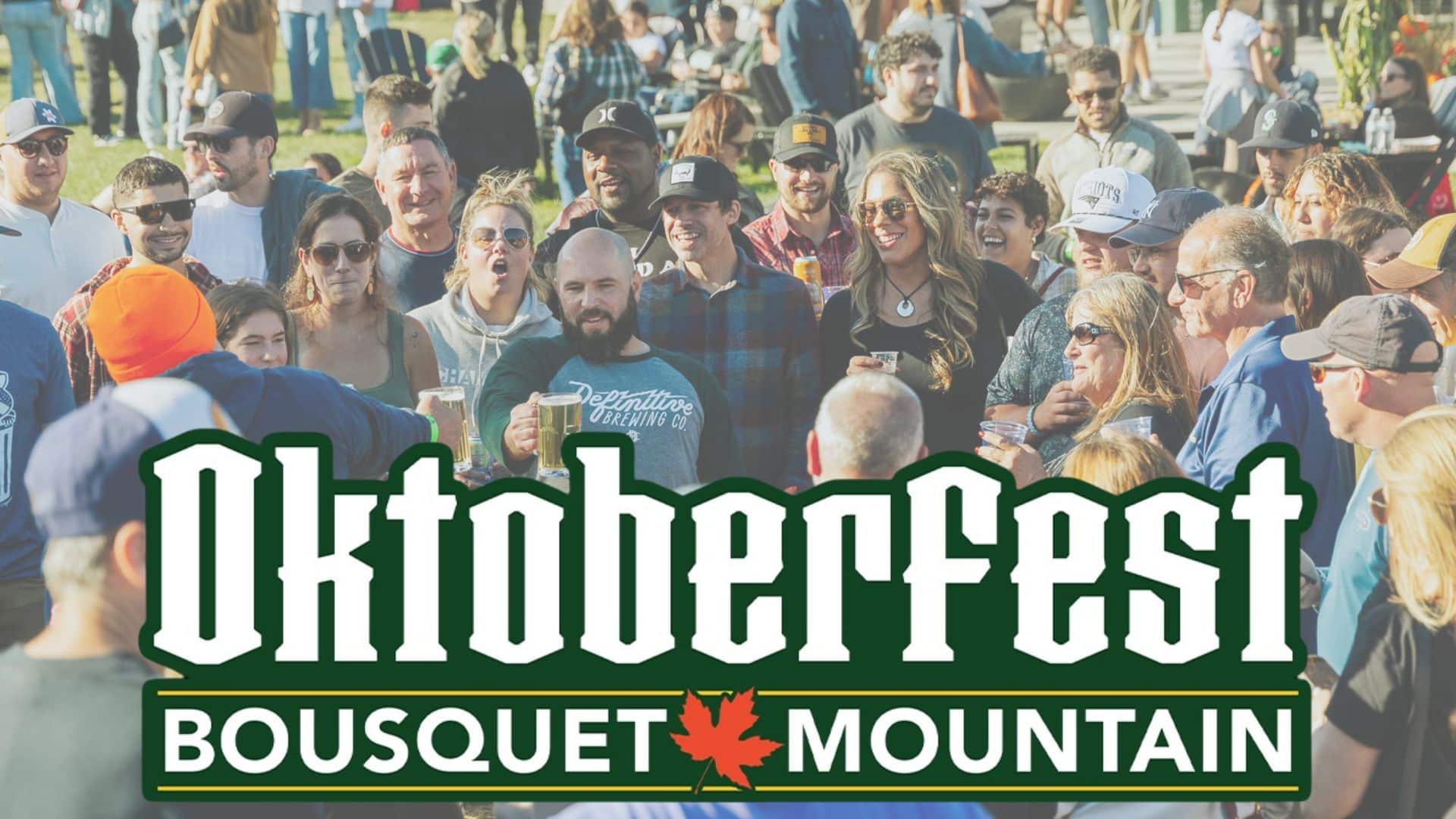 Crowd of people at an outdoor Oktoberfest festival, holding drinks with a large 'Oktoberfest' banner in the foreground. It also reads 'Bousquet Mountain' at the bottom.